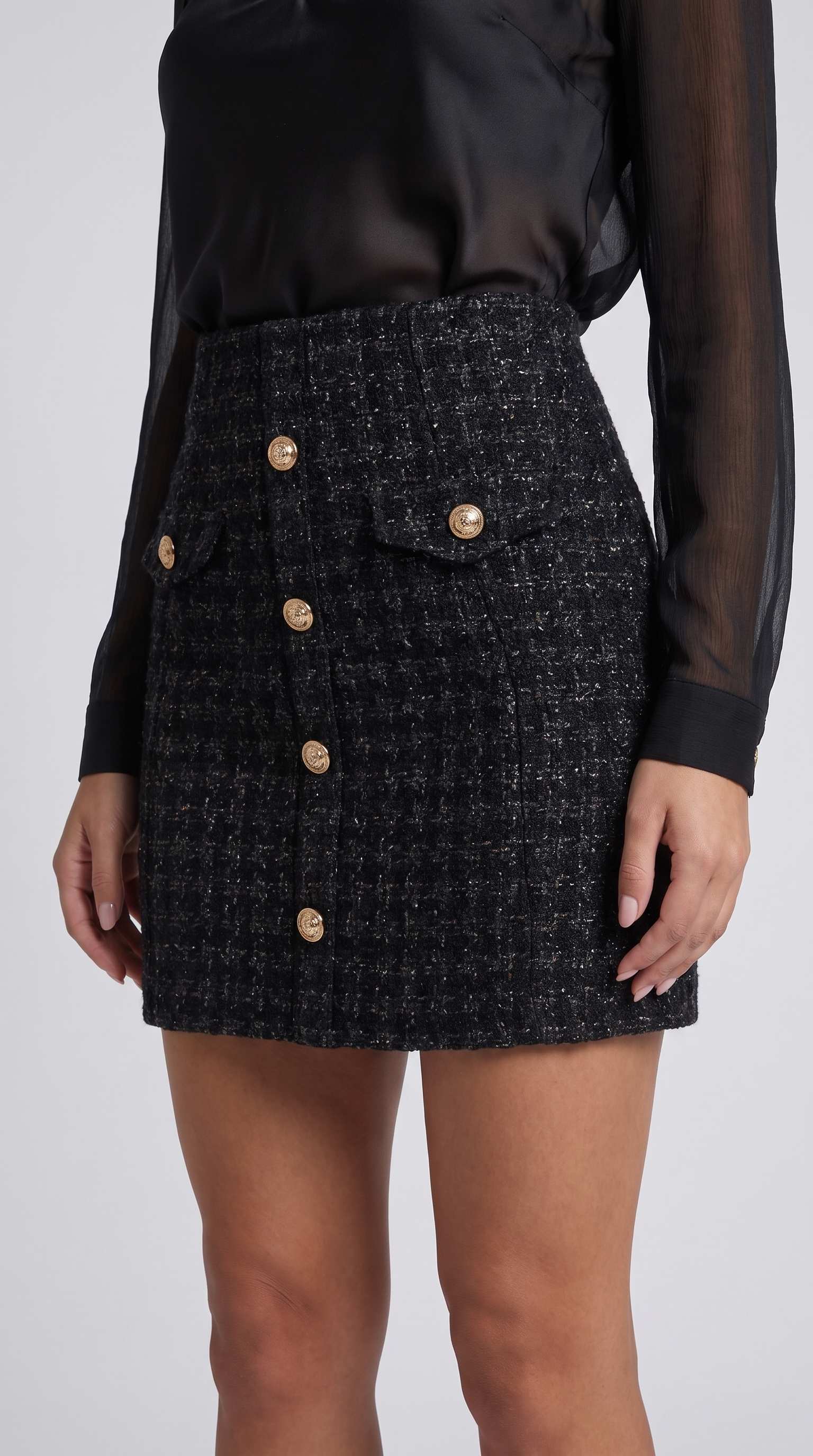 Fustă damă elegantă din tweed negru cu croială mini, nasturi aurii decorativi și finisaje premium, alegerea ideală pentru ținute business casual, office și elegante. Fustă scurtă pentru femei, confortabilă și versatilă, potrivită pentru orice sezon și numeroase combinații vestimentare.