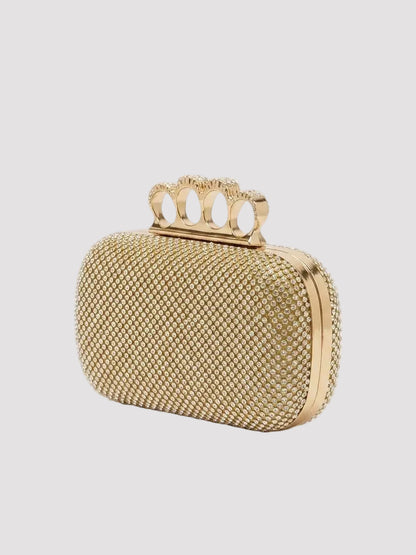Prim-plan cu geantă clutch aurie pentru damă, decorată cu cristale fine și accesoriu metalic tip inele, model elegant și sofisticat, perfect pentru ținute de seară, rochii elegante și apariții rafinate la evenimente importante.