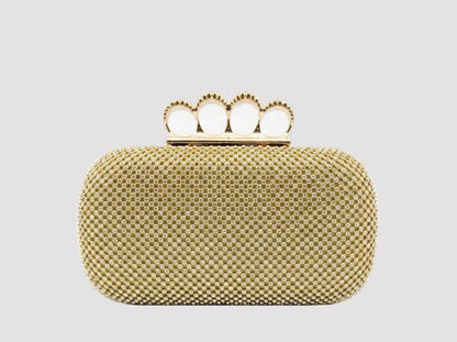 Geantă clutch aurie elegantă pentru femei, cu suprafață acoperită integral de cristale strălucitoare și mâner metalic tip inele, accesoriu de lux perfect pentru rochii de ocazie, nunți, botezuri, petreceri elegante, baluri și evenimente speciale, concepută pentru un look sofisticat și feminin.