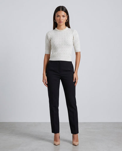 Pulover damă alb din tricot fin cu perle decorative și design modern, ideal pentru femeile care își doresc o ținută elegantă și confortabilă. Pulover premium cu mâneci scurte, recomandat pentru outfituri office, smart casual și combinații cu pantaloni, fuste sau sacouri.