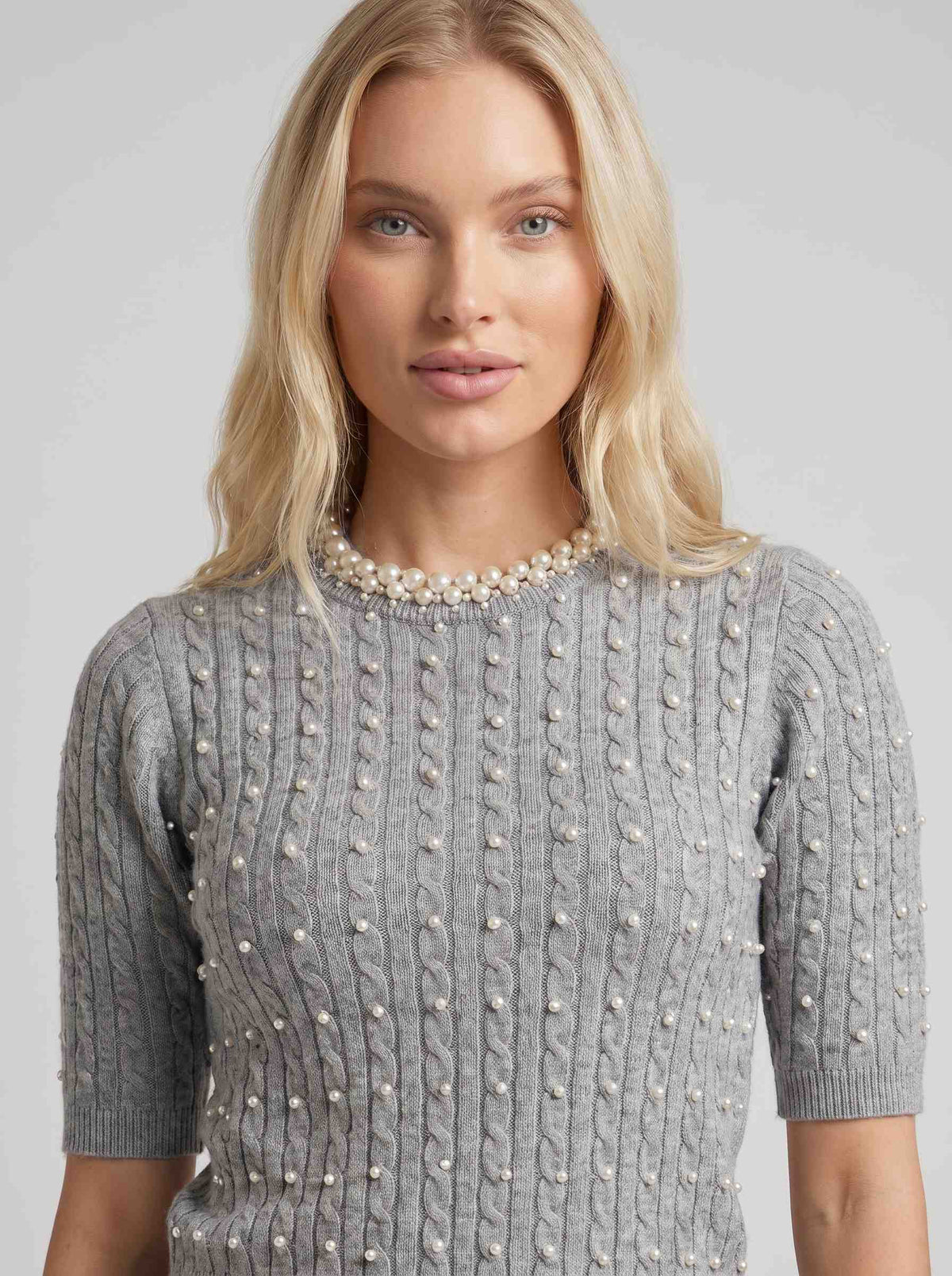 Pulover gri damă cu perle decorative, realizat din tricot premium cu mâneci scurte și croială lejeră, perfect pentru ținute office, elegante și casual. Pulover feminin modern, ideal pentru primăvară, toamnă și zilele răcoroase de vară, oferind confort și un aspect sofisticat.