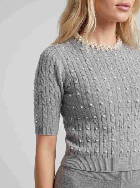 Pulover tricotat gri pentru damă cu perle decorative aplicate pe partea frontală și în jurul gulerului, mâneci scurte și croială confortabilă. Pulover elegant pentru femei, ideal pentru ținute office, casual chic, business și outfituri feminine, ușor de asortat cu jeanși, pantaloni eleganți sau fuste.
