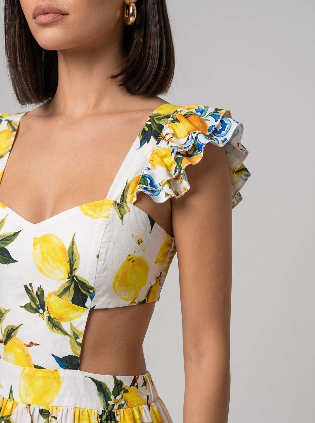 Rochie de vară lungă cu imprimeu lămâi galbene pentru femei, realizată în Italia, cu decupaje tip cut-out în talie și volane ample pentru un plus de feminitate. Rochie premium pentru damă, recomandată pentru vacanțe, garden party, petreceri pe plajă și ținute casual chic.