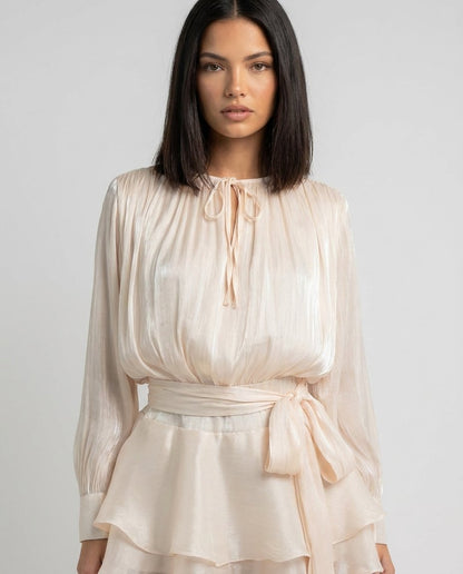 Rochie mini satinată champagne pentru damă, cu mâneci lungi bufante, fustă-pantalon integrată și talie reglabilă cu șnur, ideală pentru nunți, botezuri, cocktail-uri, petreceri și evenimente speciale. Rochie elegantă pentru femei cu aspect rafinat și modern.
