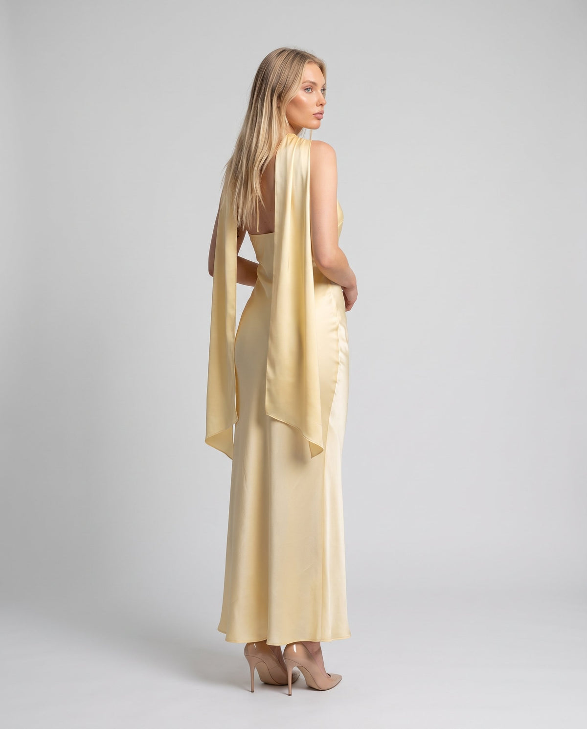 Rochie maxi galbenă satinată pentru femei, cu decolteu halter, eșarfă integrată și croială feminină care evidențiază silueta. Rochie elegantă de seară pentru damă, ideală pentru petreceri, aniversări, recepții, ceremonii și ținute glamour.