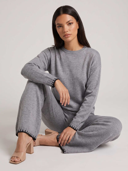 Set damă gri din tricot premium, compus din bluză modernă și pantaloni lungi cu șnur reglabil și detalii contrastante elegante. Compleu pentru femei, recomandat pentru ținute casual, city break, birou relaxat și garderoba de sezon.