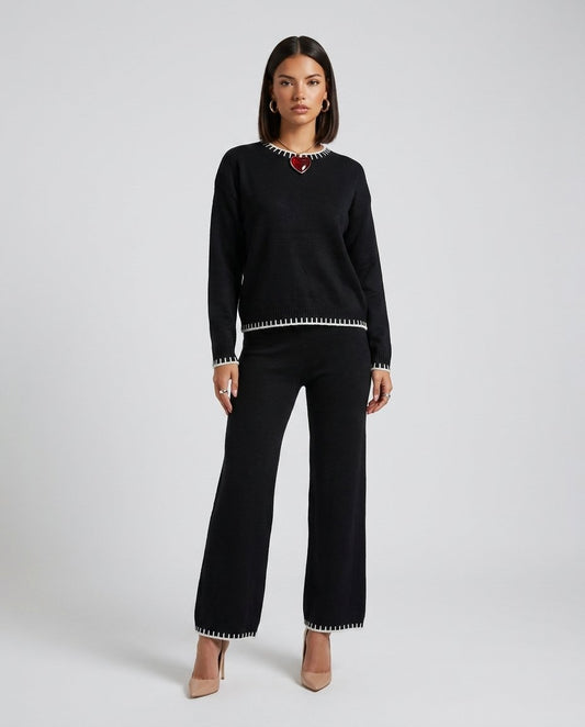 Set lounge tricot negru pentru damă, format din bluză lejeră și pantaloni lungi cu talie elastică și șnur reglabil, completat de detalii contrastante moderne. Compleu casual pentru femei, ideal pentru ținute de zi, călătorii, plimbări și confort zilnic.
