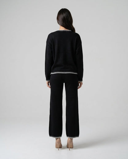 Compleu tricot negru pentru femei, cu bluză confortabilă și pantaloni lungi cu croială lejeră, realizat din material moale și plăcut la purtare. Set lounge pentru damă, perfect pentru outfituri casual chic, vacanțe, ieșiri în oraș și timpul liber.
