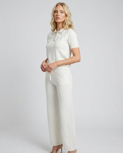 Compleu tricot alb pentru femei, cu bluză confortabilă decorată cu cristale și pantaloni lungi evazați, realizat din material moale și plăcut la purtare. Set pentru damă, perfect pentru ținute elegante de zi, birou, întâlniri și evenimente relaxate.