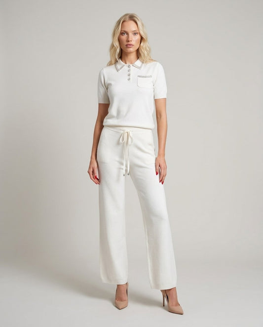 Set tricot alb pentru damă, format din bluză lejeră cu detalii strălucitoare și pantaloni evazați cu talie elastică și șnur reglabil. Compleu elegant pentru femei, ideal pentru office, ieșiri în oraș, city break, vacanțe și ținute casual chic.
