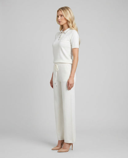 Set damă alb din tricot premium, compus din bluză modernă cu aplicații strălucitoare și pantaloni evazați cu șnur reglabil în talie. Compleu pentru femei, recomandat pentru outfituri office, casual elegante, plimbări și garderoba de sezon.