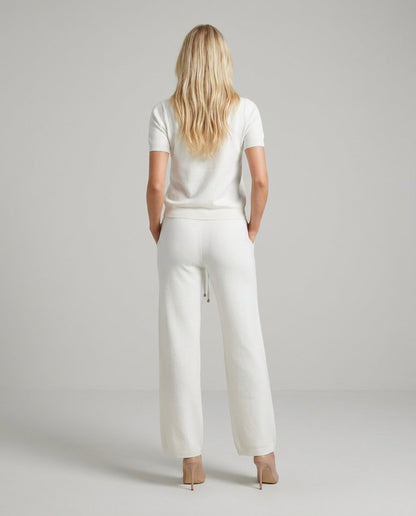 Compleu alb tricotat pentru damă, cu bluză elegantă și pantaloni evazați care alungesc vizual silueta, completat de detalii decorative cu cristale. Set pentru femei, ideal pentru birou, ieșiri în oraș, vacanțe și ținute smart casual.
