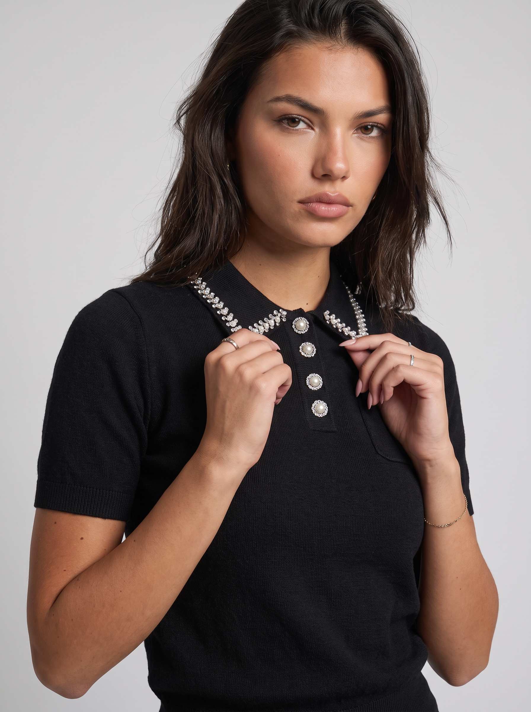 Compleu tricot negru pentru femei, cu bluză confortabilă decorată cu cristale și pantaloni lungi evazați, realizat din material moale și plăcut la purtare. Set pentru damă, perfect pentru ținute elegante de zi, birou, întâlniri și evenimente relaxate.