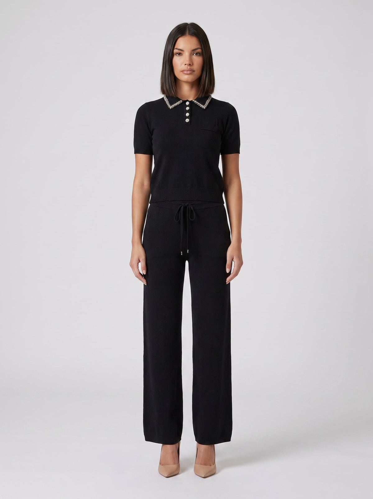 Set tricot negru pentru damă, format din bluză lejeră cu detalii strălucitoare și pantaloni evazați cu talie elastică și șnur reglabil. Compleu elegant pentru femei, ideal pentru office, ieșiri în oraș, city break, vacanțe și ținute casual chic.