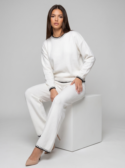 Compleu alb tricotat pentru damă cu pantaloni lungi și bluză confortabilă, croială lejeră, șnur reglabil în talie și finisaje contrastante, recomandat pentru ținute casual, relaxare, plimbări și stil minimalist elegant.